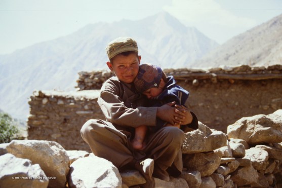 A young boy takes good care of his little brother in a Nuristan village.